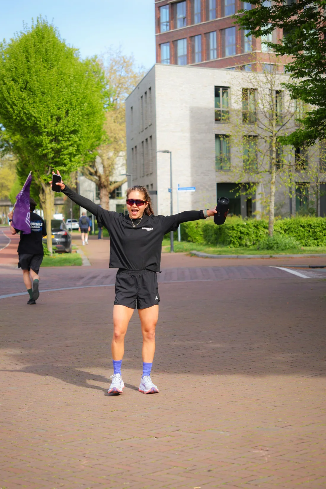 A runner celebrating with both arms raised in a city plaza
